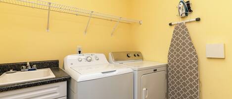 A laundry room with a washing machine, dryer, and ironing board.