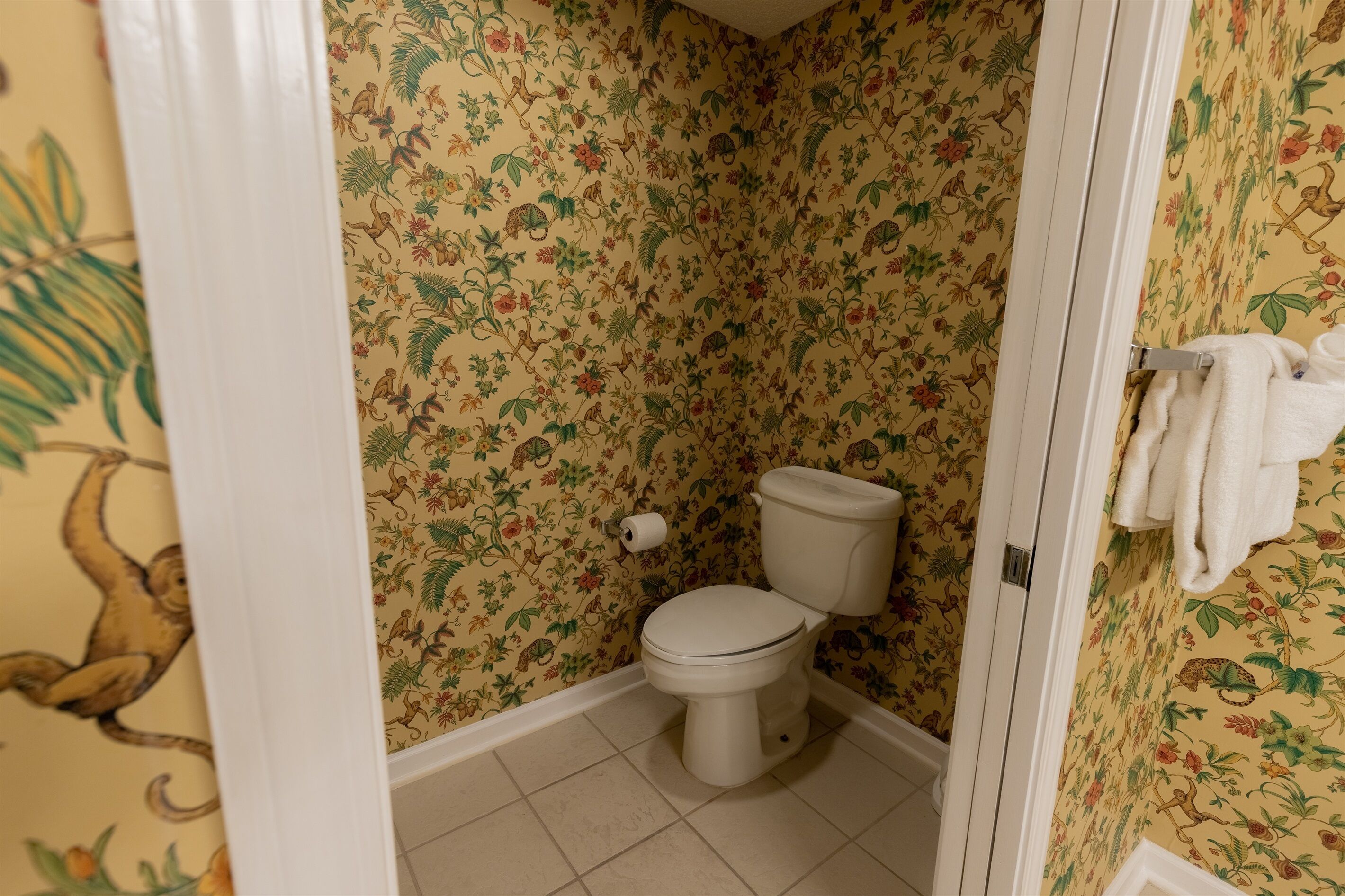 A bathroom with floral wallpaper, a toilet, and a towel rack.