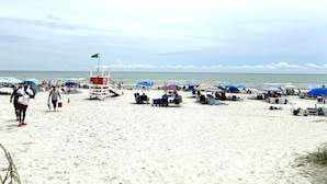 Ein Strand mit Rettungstürmen, Sonnenschirmen und Liegestühlen.