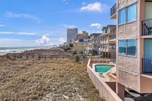 Un hôtel en bord de mer doté d’une piscine, de plusieurs balcons et d’une promenade qui mène à la plage.