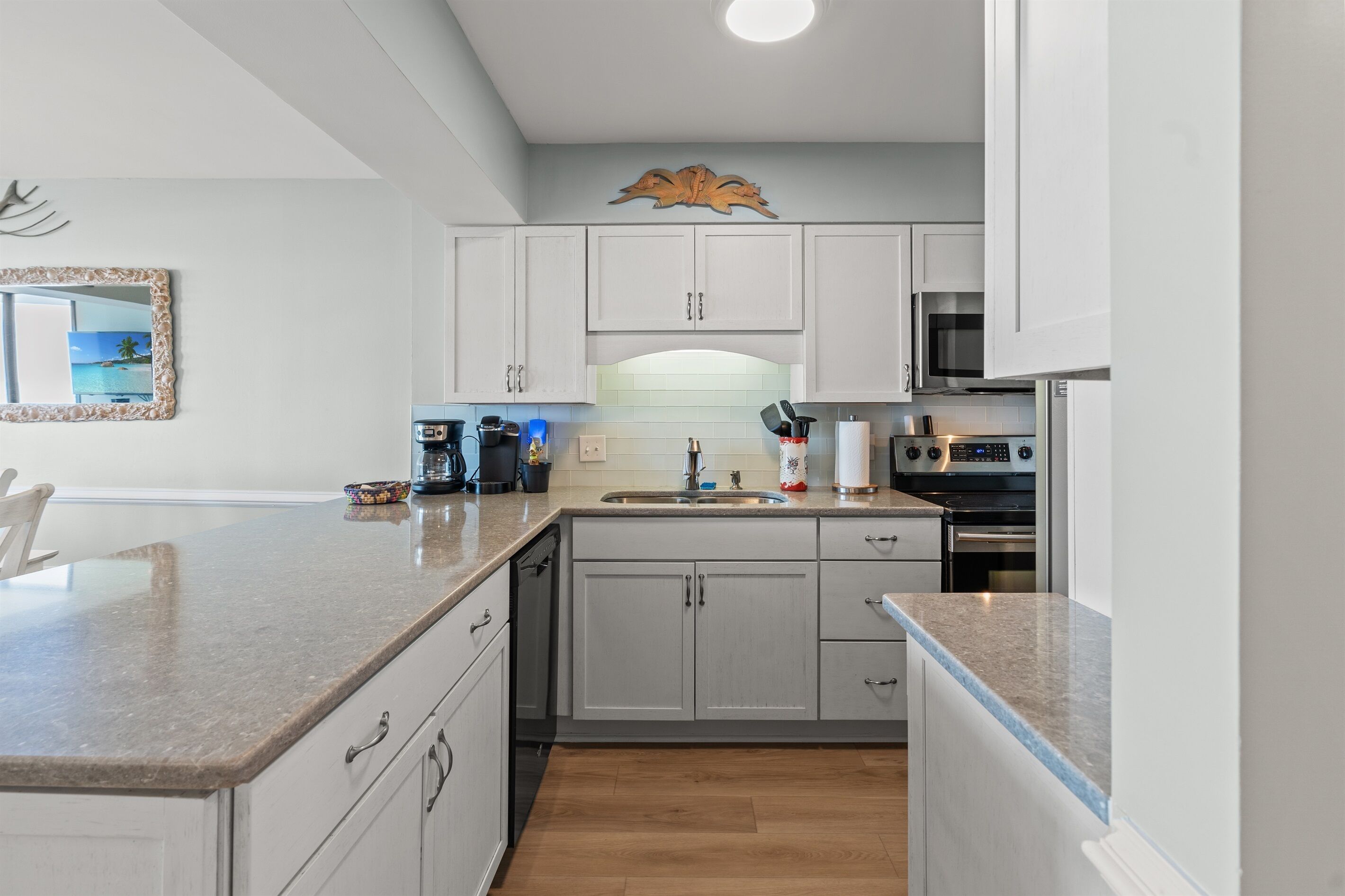 A modern kitchen with white cabinets, a granite countertop, a built-in oven, and a microwave.