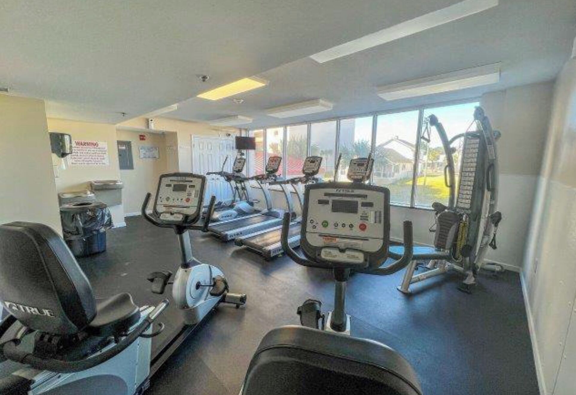 Un gimnasio con cintas de correr, bicicletas estáticas y máquinas de pesas.