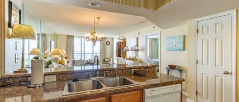A spacious kitchen with granite countertops, stainless steel appliances, and wooden cabinetry.