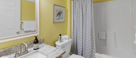 A bathroom with a sink, toilet, and shower curtain.