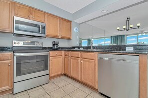 A modern kitchen with stainless steel appliances, wooden cabinets, and a dishwasher.