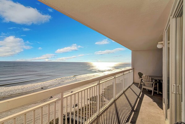 A balcony with a view of the beach and ocean.
