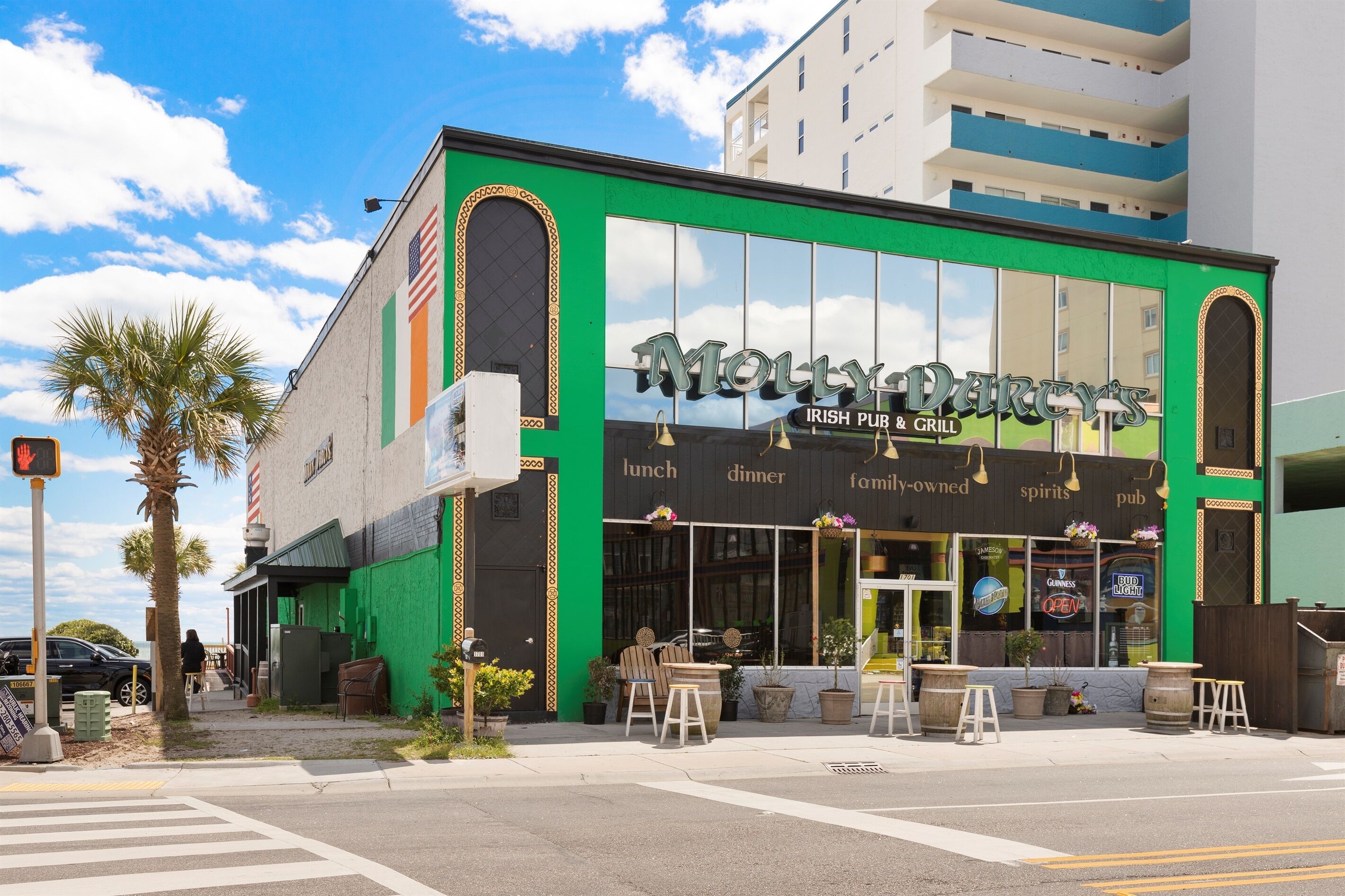 A building with a green facade, large windows, and outdoor seating.