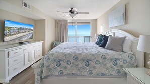 A bedroom with a bed, a television, a ceiling fan, a window with curtains, and a view of the ocean. - Crescent Shores 1601 Oceanfront, Pools,Lazy River (North Myrtle Beach)