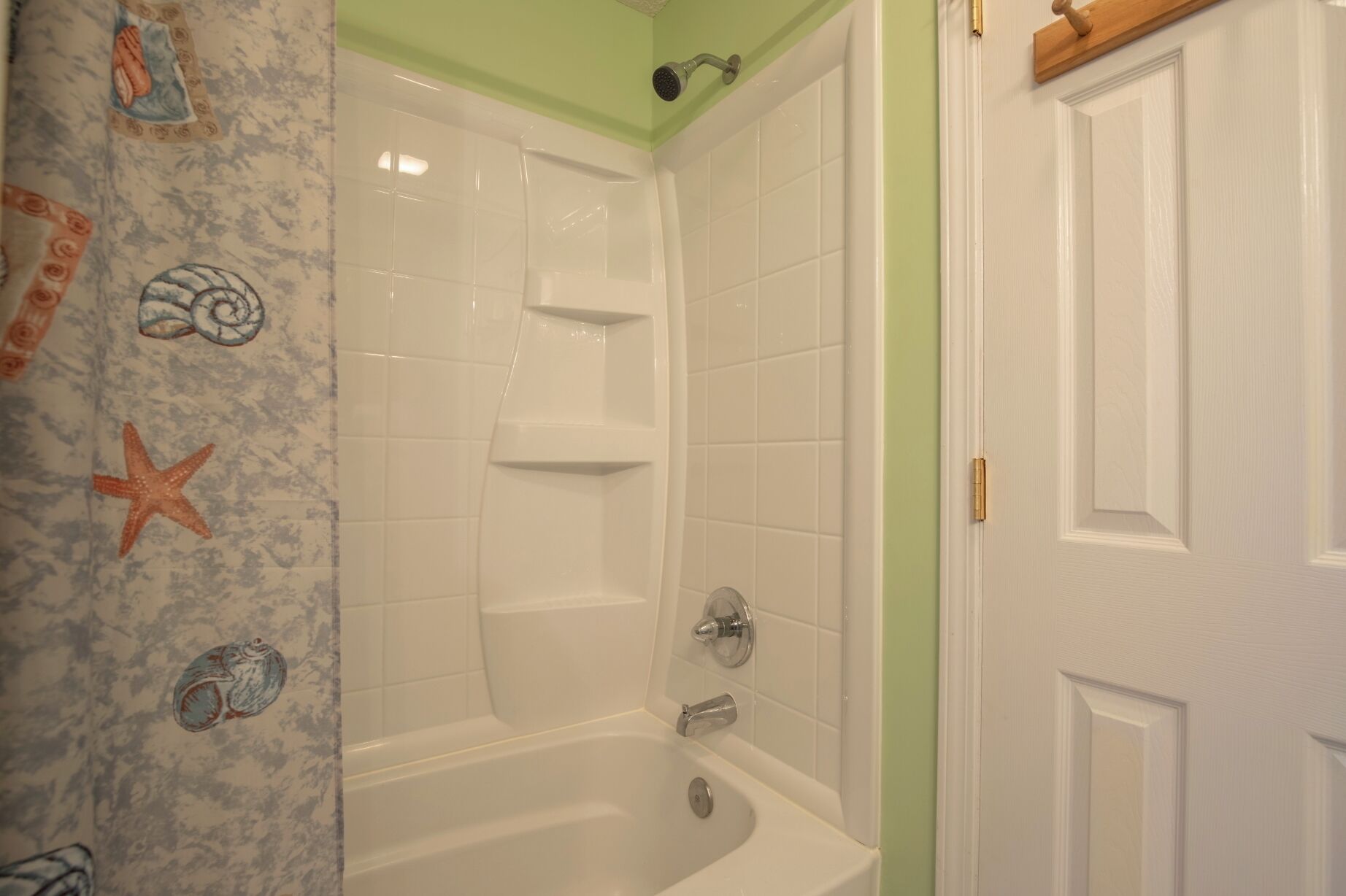 Une salle de bain avec une baignoire blanche, une douche et une porte dotée d’une poignée dorée.