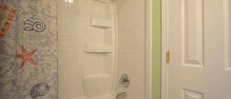 Une salle de bain avec une baignoire blanche, une douche et une porte dotée d’une poignée dorée.
