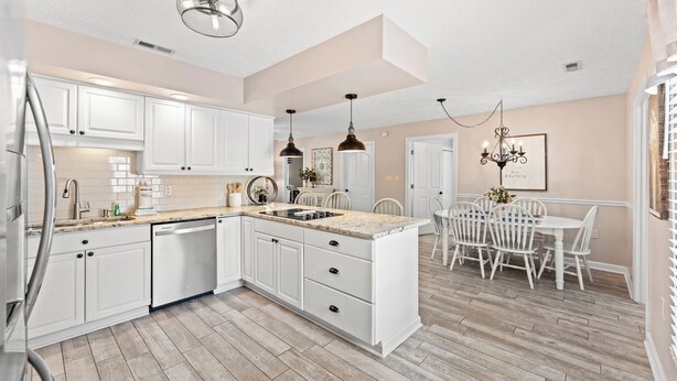 A kitchen with white cabinets, a dining area with white chairs, and a chandelier. - "Lowery" House w/private pool Free Golf Cart use (North Myrtle Beach)