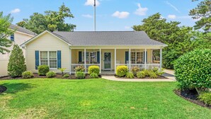 A single-story house with a front porch, a small garden, and a clear sky. - "Lowery" House w/private pool Free Golf Cart use (North Myrtle Beach)