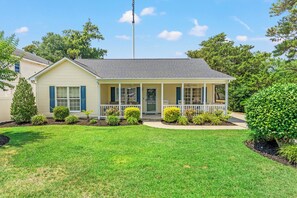 A single-story house with a front porch, a small garden, and a clear sky.