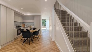 Una cocina moderna con zona de comedor, una escalera y vistas al exterior.