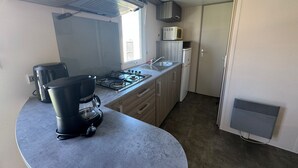 Une cuisine compacte équipée d’une cuisinière à gaz, d’une machine à café, d’un four à micro-ondes et d’un petit réfrigérateur.