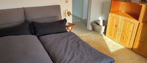 Ein Schlafzimmer mit einem Bett, einem Holzschrank und einem kleinen Tisch.