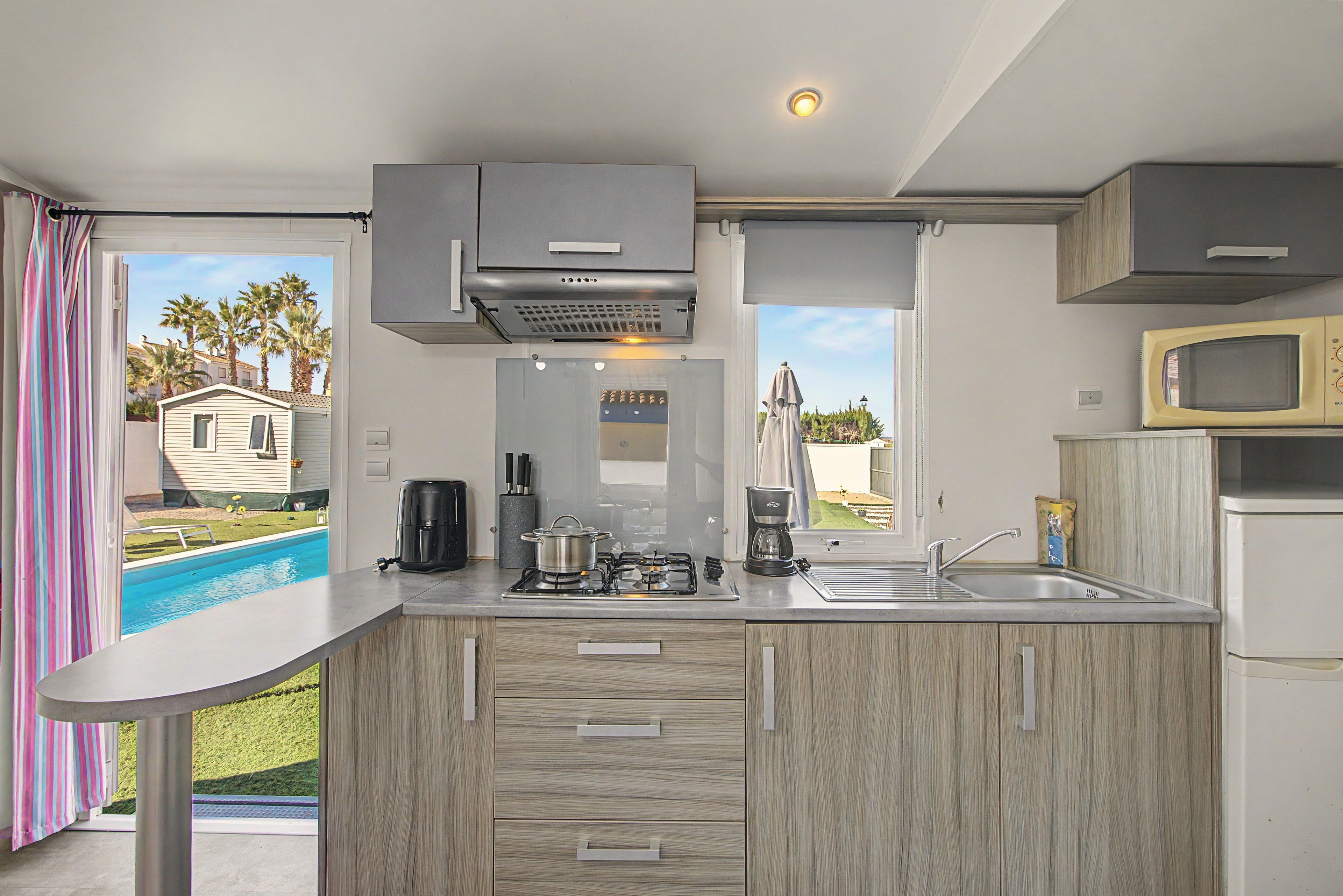 Cocina compacta con estufa a gas, cafetera y microondas.