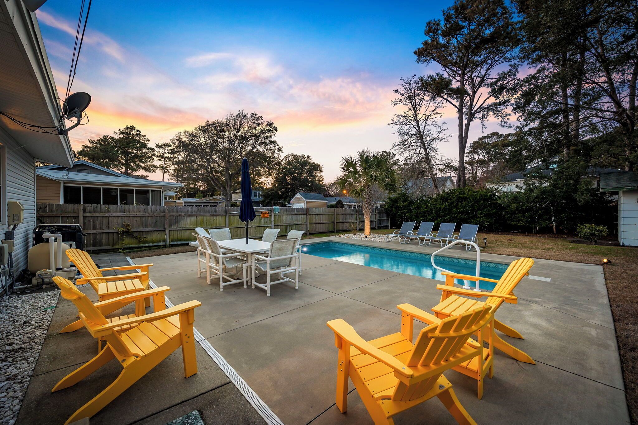 A backyard with a pool, outdoor furniture, and a wooden fence.