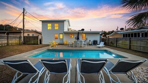 Ein Garten mit Swimmingpool, Liegestühlen und Holzzaun.