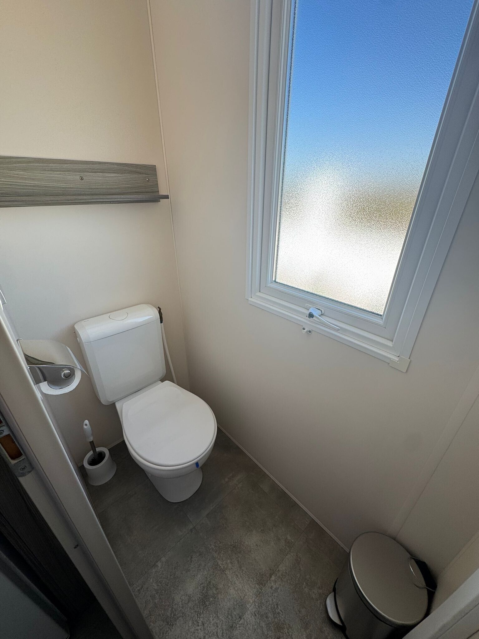 Un baño pequeño y moderno con inodoro, bidé y ventana.