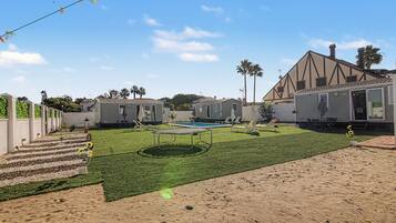 Un barrio residencial con varias casas móviles, una piscina, un trampolín y una zona arenosa.