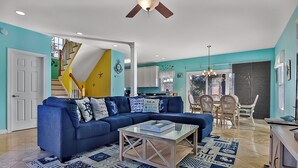 Een woonkamer met een blauwe bank, een glazen salontafel en een kamerbreed tapijt met een patroon.