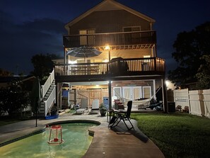 Ein zweigeschossiges Haus mit Balkon, Swimmingpool und Gartenmöbeln.