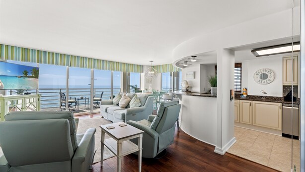 A modern living room with a view of the ocean, a kitchen with a curved island, and a dining area with a view. - N Hampton 1402 in Kingston, Oceanfront, Pool,Beach (Myrtle Beach)