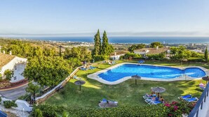 Una piscina con vista sull'oceano, circondata da vegetazione e qualche sedia a sdraio.