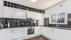 Una cucina moderna con mobili bianchi, una cappa in acciaio inossidabile e un forno integrato.