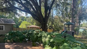 A wooden deck with large green plants, a gazebo, and a slide in a backyard setting. - Friendly Home Near Downtown UL - Fenced Yard (Lafayette)
