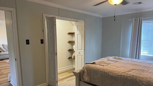 A bedroom with a bed, a ceiling fan, and a door leading to a hallway. - Friendly Home Near Downtown UL - Fenced Yard (Lafayette)