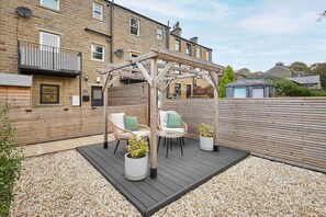 A wooden deck with outdoor furniture, a pergola, and a garden area with potted plants. - Host Stay Holmfirth Hideaway (Holmfirth)