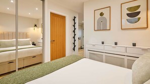A modern bedroom with a bed, a wooden door, a coat rack, and wall art. - Host Stay Holmfirth Hideaway (Holmfirth)