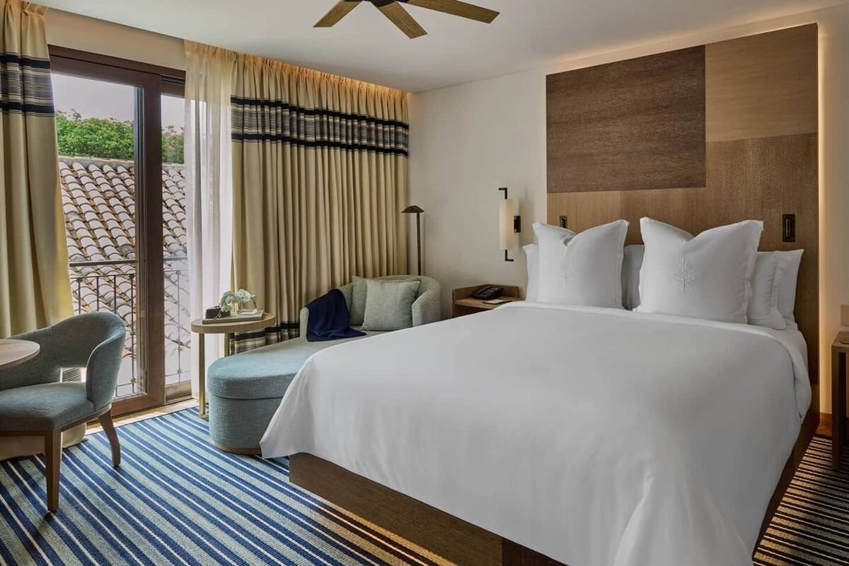 Een hotelkamer met een groot bed, een bureau, een stoel en uitzicht op de omgeving.