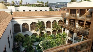 Un immeuble à plusieurs étages doté d’une cour intérieure agrémentée de palmiers et d’une piscine.