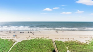A beach with a wooden boardwalk leading to the water, sandy beach, and a clear sky. - San-A-Bel #501 Adorable Oceanfront End Unit (North Myrtle Beach)