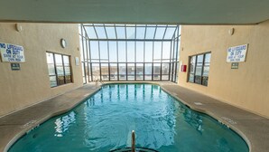 An indoor swimming pool with clear glass walls, no lifeguard on duty signs, and a view of the outside. - San-A-Bel #501 Adorable Oceanfront End Unit (North Myrtle Beach)