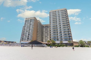 A high-rise hotel with multiple balconies, a beach in the foreground, and palm trees. - Sands Beach Club #324,Oceanfront, Pool (Myrtle Beach)