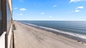 A beach view from a balcony with a clear sky and calm sea. - Sands Beach Club 814, End Unit Sunsets & Pools (Myrtle Beach)