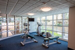 A gym with exercise equipment, large windows, and a view of the outdoors.