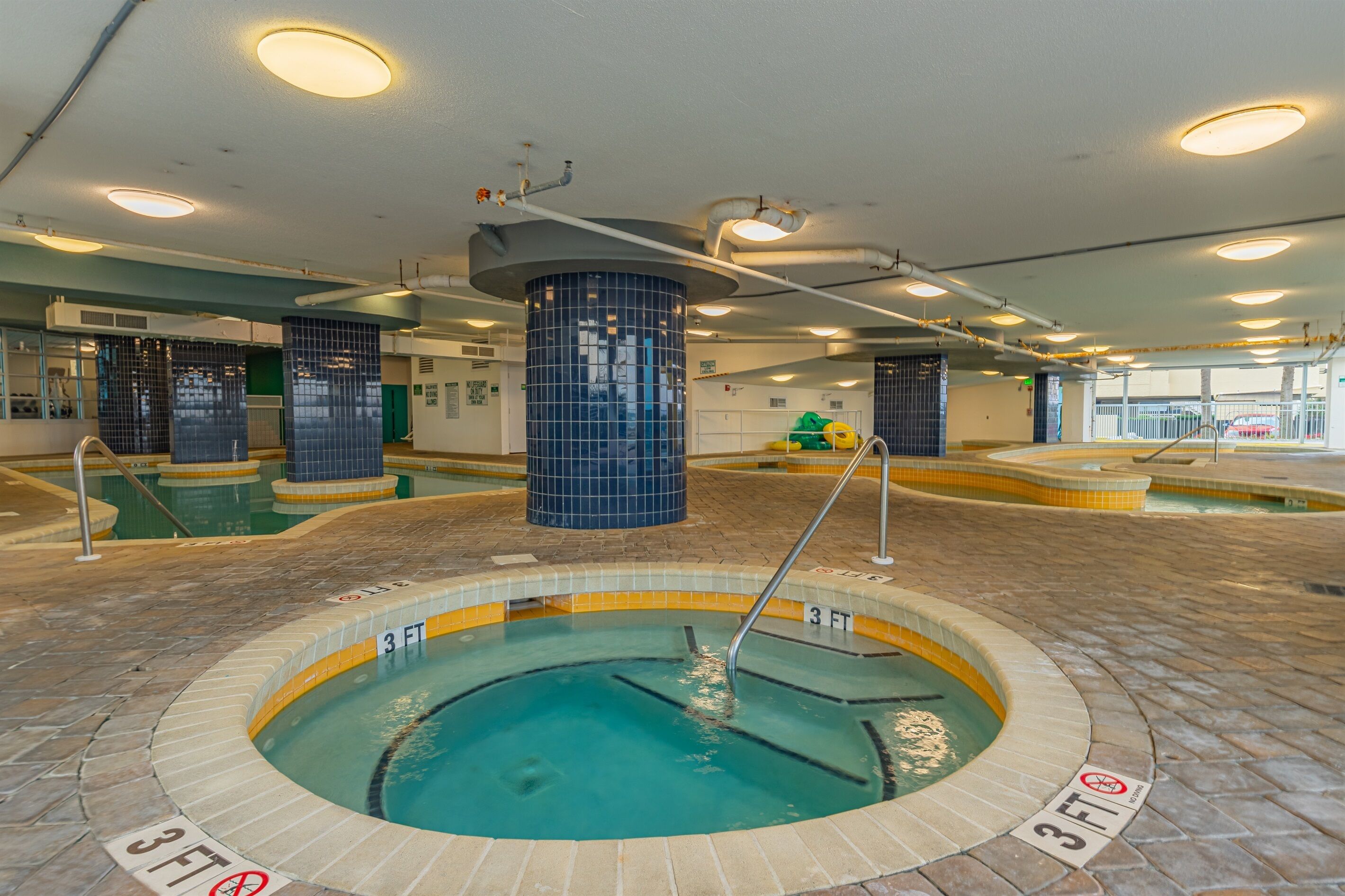 Una piscina con un indicador de profundidad de 90 centímetros, paredes de azulejos y una columna central.