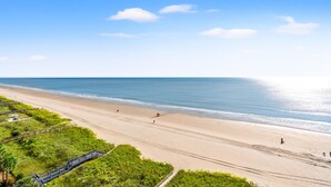 En strand med en träpromenad, sandstrand och klarblå himmel.