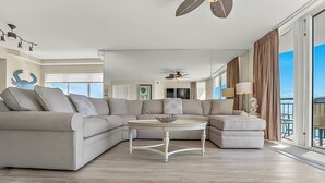 Un salon moderne avec un canapé d’angle, une table basse ronde et un ventilateur de plafond.