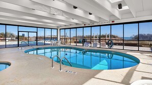Ein Hallenbad mit freiem Blick auf den Strand und den Ozean durch große Fenster.