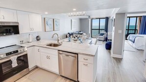 A modern kitchen with white cabinets, stainless steel appliances, and a large island with a sink. - WaterPointe II #905-Oceanfront Treasure-Pools,Gym (North Myrtle Beach)