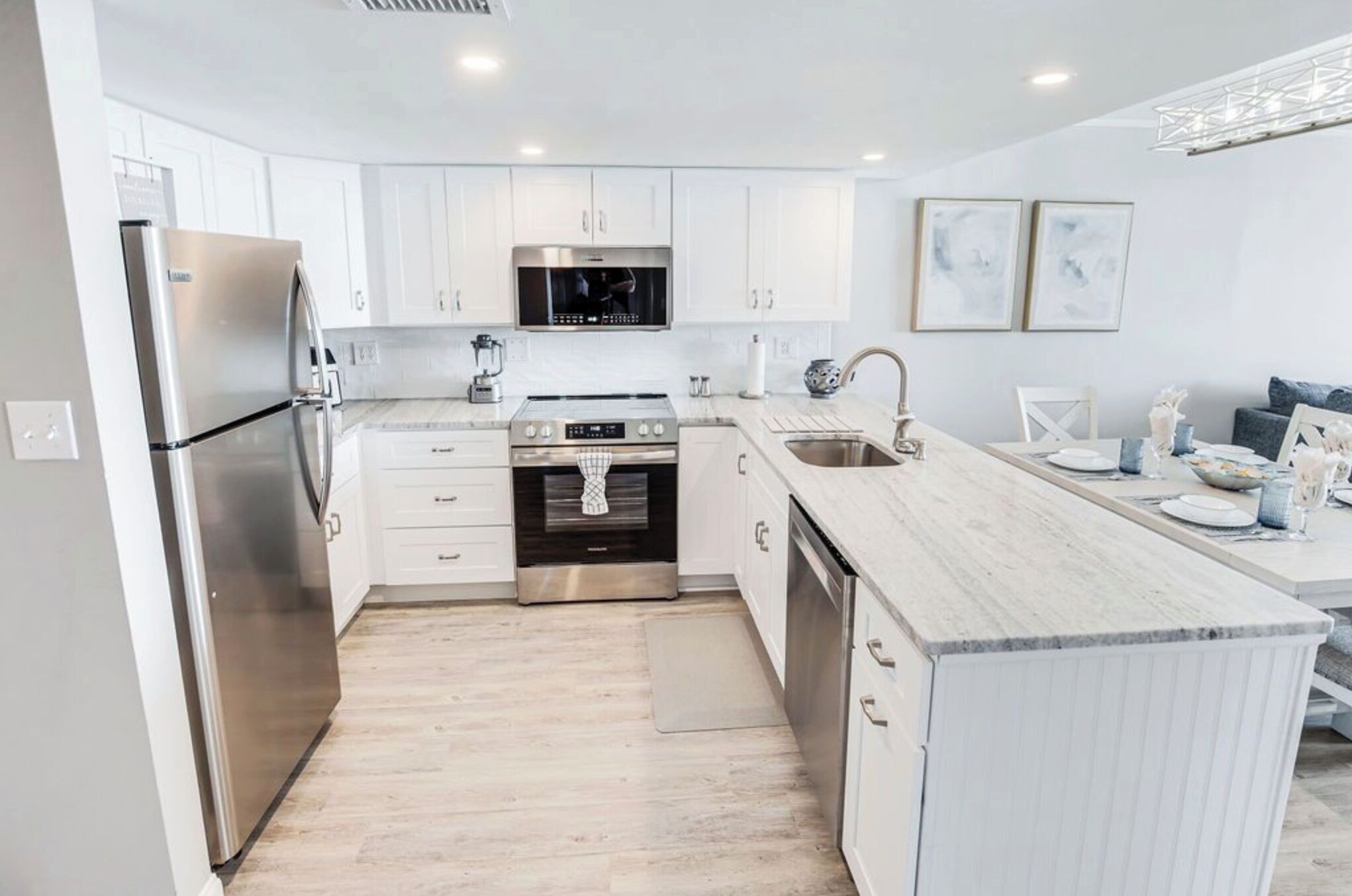 A modern kitchen with white cabinetry, stainless steel appliances, and a marble countertop.