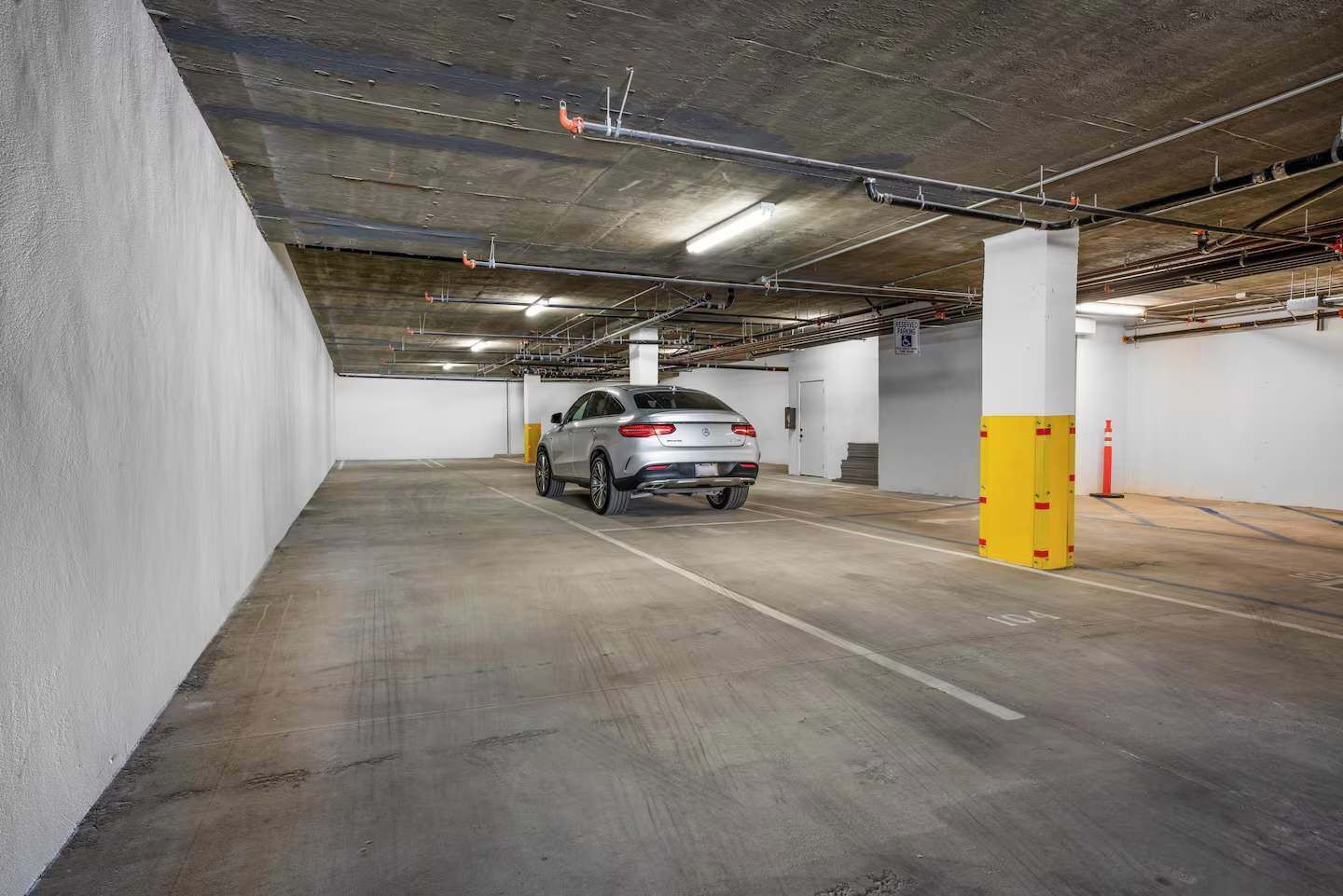 A parking garage with a white car parked in a spot.