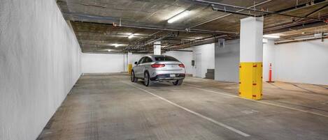 A parking garage with a white car parked in a spot.