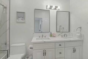A modern bathroom with a white sink, double mirrors, and a toilet.